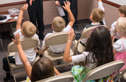 Primary children raising their hands in class